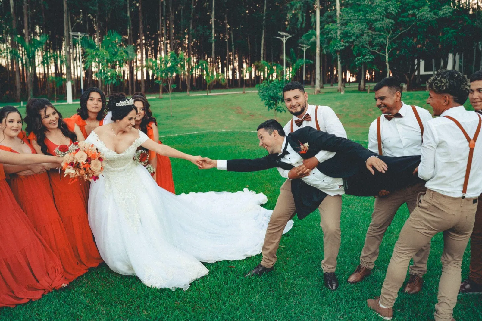Wedding party playfully tugging the bride across the lawn